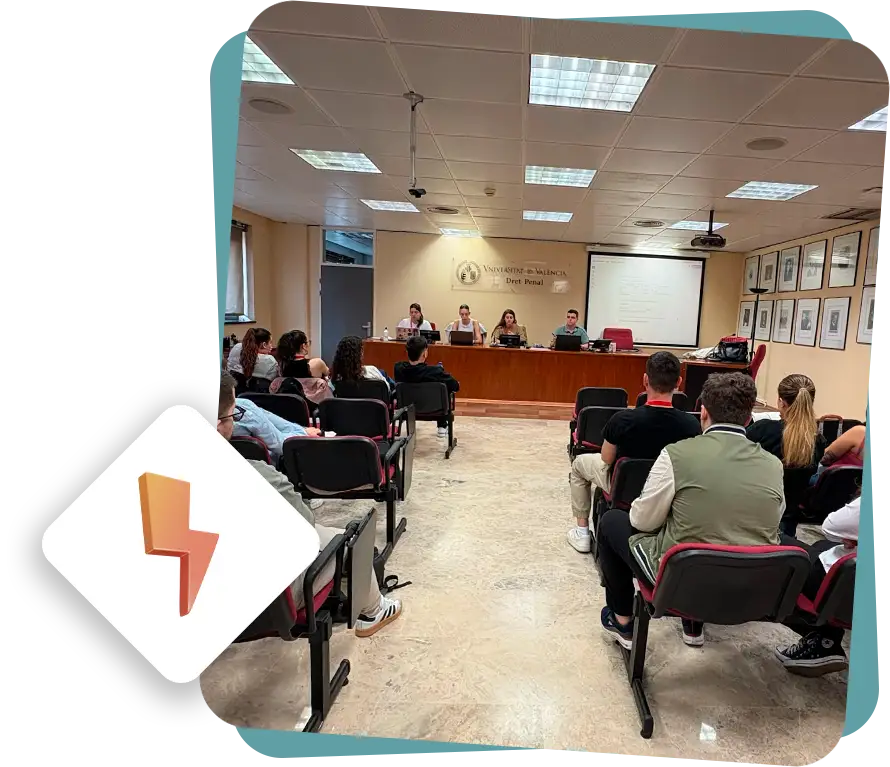 Sala de conferencias con gente sentada y ponentes al fondo.